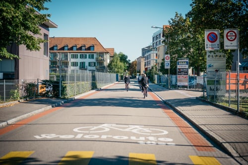 Radweg mit zwei Radfahrern in einer urbanen Umgebung.