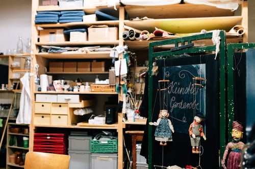 Werkstatt mit Regalen voller Materialien und Puppen.