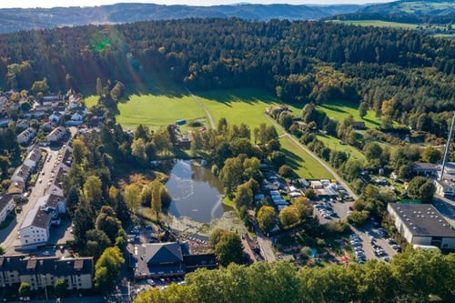 Luftaufnahme einer Stadt mit Park, Häusern und Wäldern.