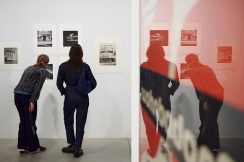 Zwei Personen betrachten ausgestellte Bilder in einer Galerie.