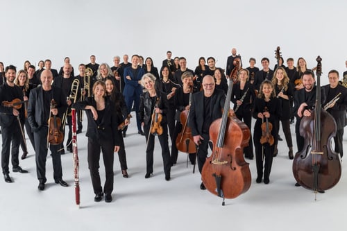 Grosse Gruppe von Menschen in schwarzer Kleidung mit Musikinstrumenten.