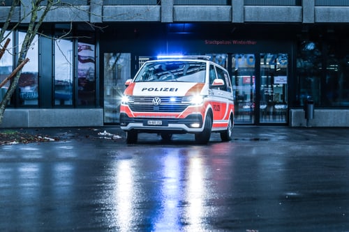 Polizeiauto mit eingeschaltetem Blaulicht vor einem Gebäude.