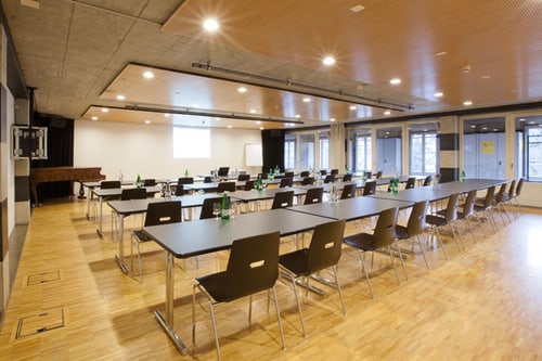 Leerer Konferenzraum mit langen Tischen und Stühlen.