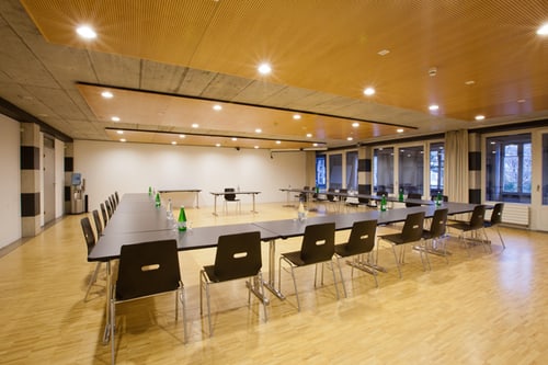 Konferenzraum mit rechteckigem Tischarrangement und leeren Stühlen.
