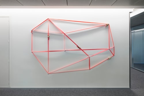 Geometrische rote Wandkunst in modernem Innenraum.
