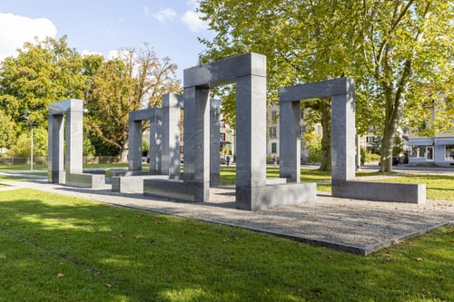 Moderne Steinskulpturen auf einer grünen Wiese in einem Park.