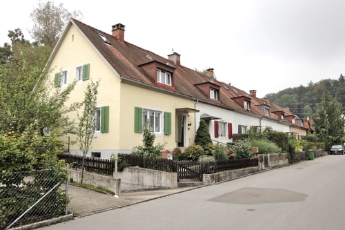 Reihe von Häusern mit schrägen Dächern und Fensterläden an einer ruhigen Strasse.