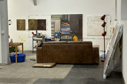 Künstleratelier mit Sofa und Gemälden an den Wänden.