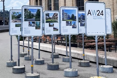 Mehrere Infotafeln auf Betonständern in einer städtischen Umgebung.