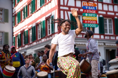 Person tanzt fröhlich in bunter Strassenveranstaltung.