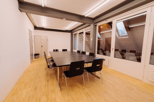 Konferenzraum mit grossem Tisch und Stühlen.