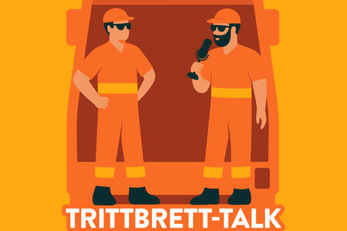 Zwei Personen in orangefarbener Kleidung stehen vor einem Fahrzeug und sprechen in ein Mikrofon.