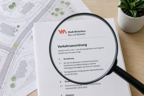 Lupenvergrösserung einer Verkehrsanordnung auf einem Schreibtisch mit Plänen.
