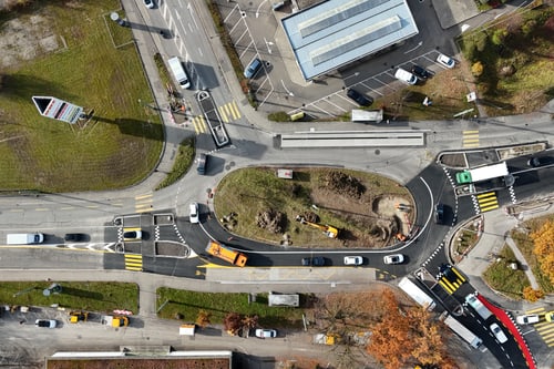 Luftaufnahme eines Verkehrskreisels mit Autos und Umgebung.