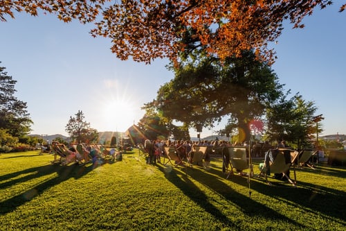 Menschen auf Liegestühlen im Park bei Sonnenuntergang.