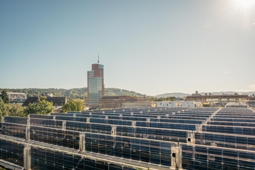 Solarmodule auf einem Dach mit Stadt im Hintergrund.