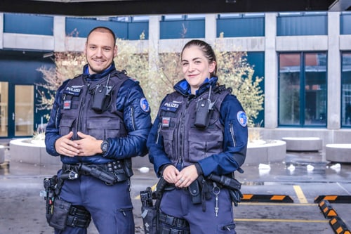 Zwei Personen in Polizeiuniformen stehen draussen.