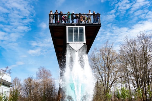 Gruppe von Menschen auf einer überhängenden Plattform über fallendem Wasser.