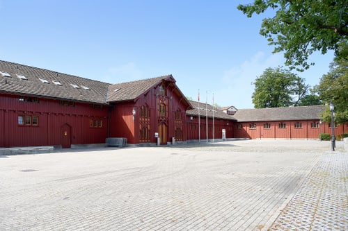 Gebäude MZA Teuchelweiher mit gepflastertem Hof und Bäumen.