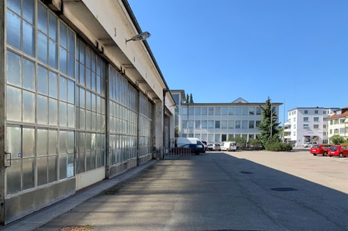 Industriegebäude und geparkte Autos bei sonnigem Wetter.