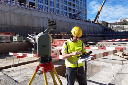 Bauarbeiter mit gelbem Helm bei Baustelle.