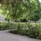 Garten mit Bäumen, Blumen und historischem Gebäude.