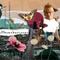 Collage mit einer Frau, Schmetterlingen, Vögeln und Blumen über einer Stadtlandschaft.