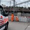 Zwei Personen in orangefarbener Kleidung arbeiten neben einem Fahrzeug mit rot-weissen Markierungen.