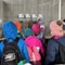 Kinder in bunten Jacken schauen sich Ausstellung an.