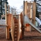 Holzspielplatz mit Rutschen und Netzen.