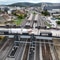 Luftaufnahme eines Bahnhofs mit mehreren Gleisen und Gebäuden im Hintergrund.