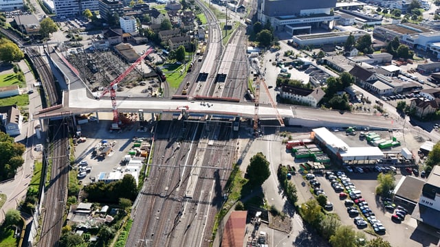 Luftaufnahme einer Brückenbaustelle über Bahnstrecken in einer Stadt.