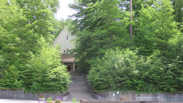 Abdankungskapelle Friedhof Rosenberg hinter Bäumen und Treppen.