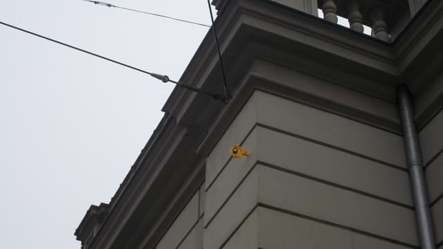 Ecke eines historischen Gebäudes mit beige Fassaden und einem kleinen Vogelmodell.