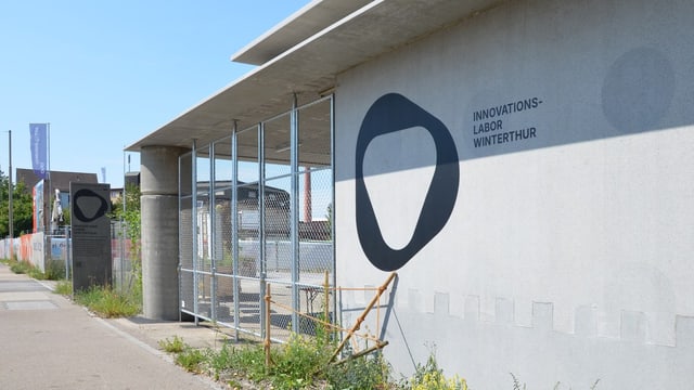 Modernes Gebäude mit Gitterzaun und Graffiti auf der Wand.