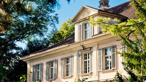 Historisches Gebäude mit Bäumen im Vordergrund.