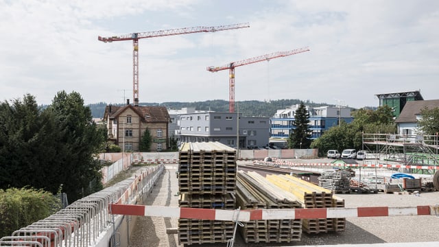 Baustelle mit Kränen und gestapelten Baumaterialien.