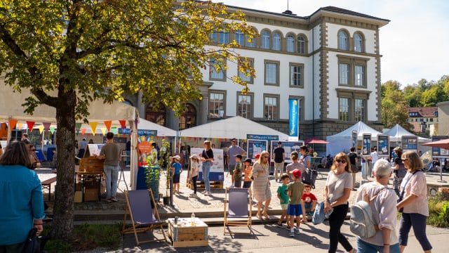 Menschen schlendern über den belebten Klimatag vor dem Technikumgebäude.