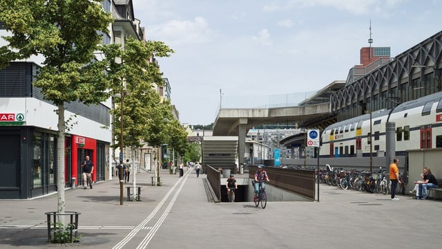 Städtische Strassenszene mit Zug und Radfahrer.