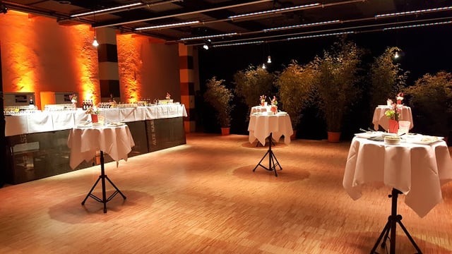 Leerer Bankettraum mit dekorierten Stehtischen und Buffet.