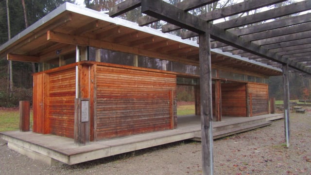 Holzgebäude im Freien mit umliegenden Bäumen.