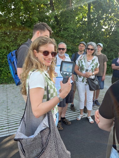 Gruppe von Menschen draussen, eine Person hält ein Gerät.