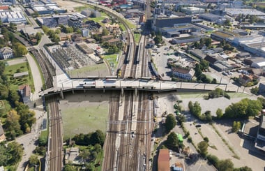 Luftaufnahme eines Bahnhofs mit mehreren Bahngleisen und umliegenden Gebäuden.
