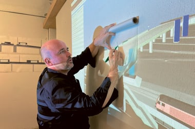 Person zeichnet auf Projektion eines Bauplans an der Wand.
