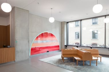 Heller Raum mit buntem Wandbild und Holzbänken.