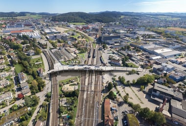 Luftaufnahme einer Stadt mit Bahngleisen und Gebäuden.