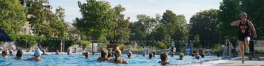 Menschen schwimmen in einem Freibad.