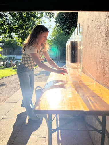 Person an einem Holztisch im Freien mit Lichteinfall.