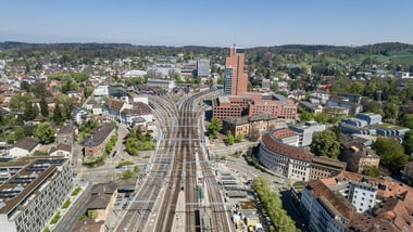 Luftaufnahme einer Stadt mit Eisenbahnschienen und Bürogebäuden.