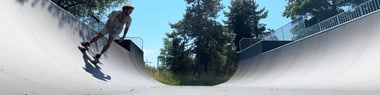 Person fährt Skateboard in Halfpipe bei Tageslicht.